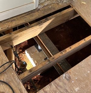 The floor opened from inside, looking down at the new concrete footing poured for the replacement support.
