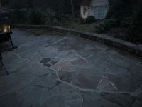 The flagstone patio at dusk, the stacked stone wall running along its outer edge.