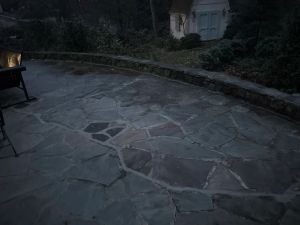 The flagstone patio at dusk, the stacked stone wall running along its outer edge.
