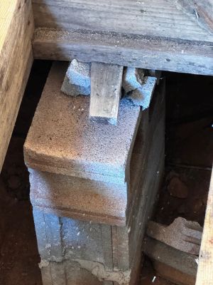 Before: a crumbling block pier under the floor framing, the top course spalling apart beneath the beam.