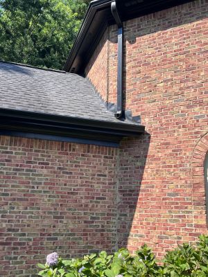 The upper brick wall where it meets the lower roof after the work, flashing in place along the roof line.