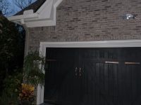 The detached brick garage from the side, the brickwork continuous above the doors.