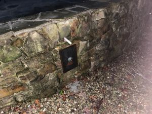 A steel anchor plate bolted through the stacked stone wall, fresh mortar along the cap above it.