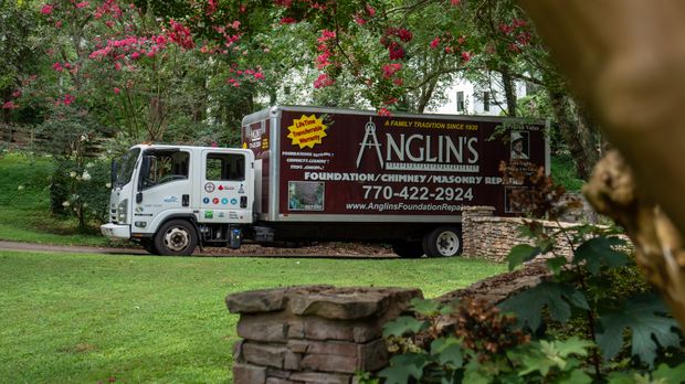 An Anglin's truck parked under blooming crape myrtles, its side panel reading Foundation, Chimney and Masonry Repairs, a family tradition since 1930.
