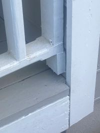 Close view of the painted porch step and post where they meet, after the porch was raised back up.