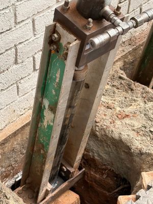 Close view of the driving head bolted to the pier bracket, the green pier tube running down into the hole.