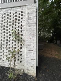 Painted brick lattice wall and the solid brick column at the corner of the house, below the deck.