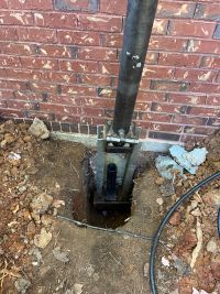 The pier bracket bolted under the footing, the pier tube running down into the ground.