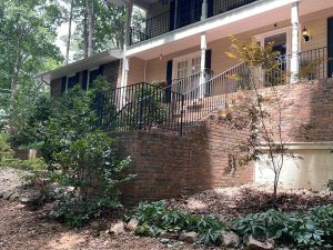 The brick retaining wall and steps at the front of the house, iron railings running up to the porch.