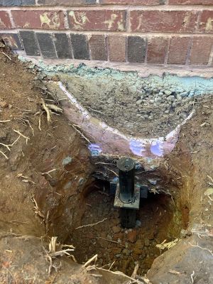 A steel pier and its bracket set in the excavation beneath the brick footing.