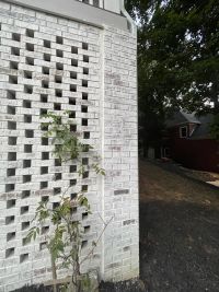 The same brick column and lattice wall from the side, downspout running down the corner.