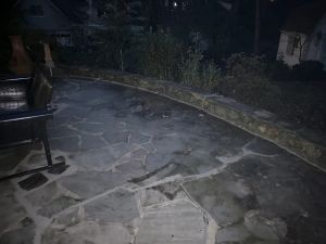 The curve of the stacked stone wall following the edge of the flagstone patio.