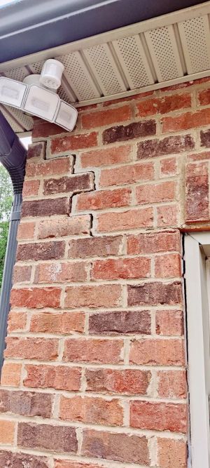 Before: a stair-step crack in the brick at the garage corner, running down from under the eave.