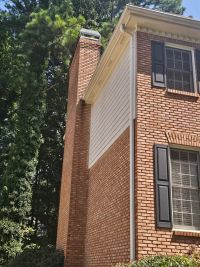 The tall brick chimney rising past the roof line at the side of the house.
