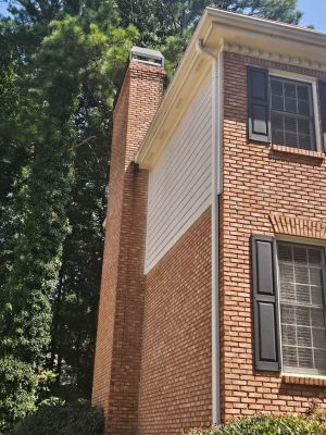 The tall brick chimney rising past the roof line at the side of the house.