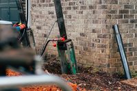A driven steel pier installed beside a foundation wall, carrying the house on steel instead of soil.