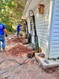 Anglin's crew working the line of piers along the outbuilding, spoil piled beside the open excavation.