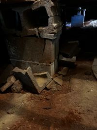 Before: the same block pier in the crawl space, broken pieces piled on the ground at its base.
