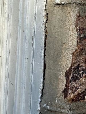Close view of the gap opened between the painted trim and the masonry beside it.