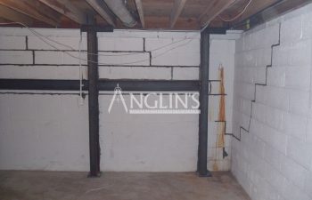steel support beams in a basement of a bulding and with cracks between the bricks filled