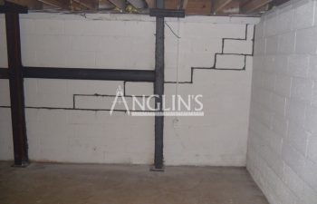 steel support beams in a basement of a bulding and with cracks between the bricks filled
