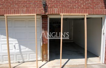 two wooden support frames in front of garage doors which need repair
