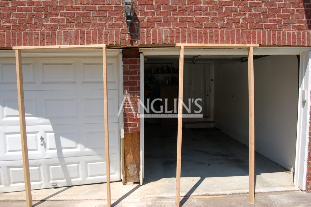two wooden support frames in front of garage doors which need repair