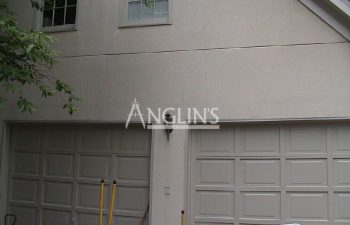 wall with 2 garage doors with a crack above one of the doors that was fixed