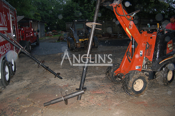 skid steer with a drill ready to dig into the ground