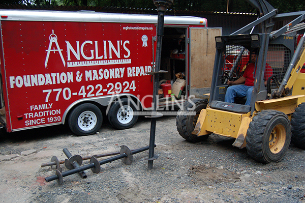 anglin employee in a skid steer digging a hole next to an anglin trailer
