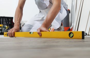 Man worker with a bubble level checking if the floor is level.