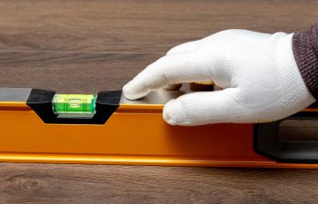 A contractor checking wooden floor level with a leveling instrument.