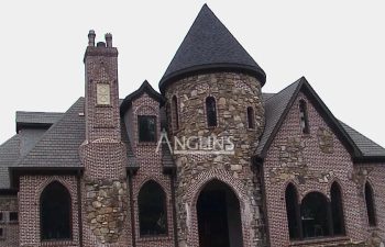 Stone and brick house with a steep roof and round turret, featuring the word "Anglin's" on the front.